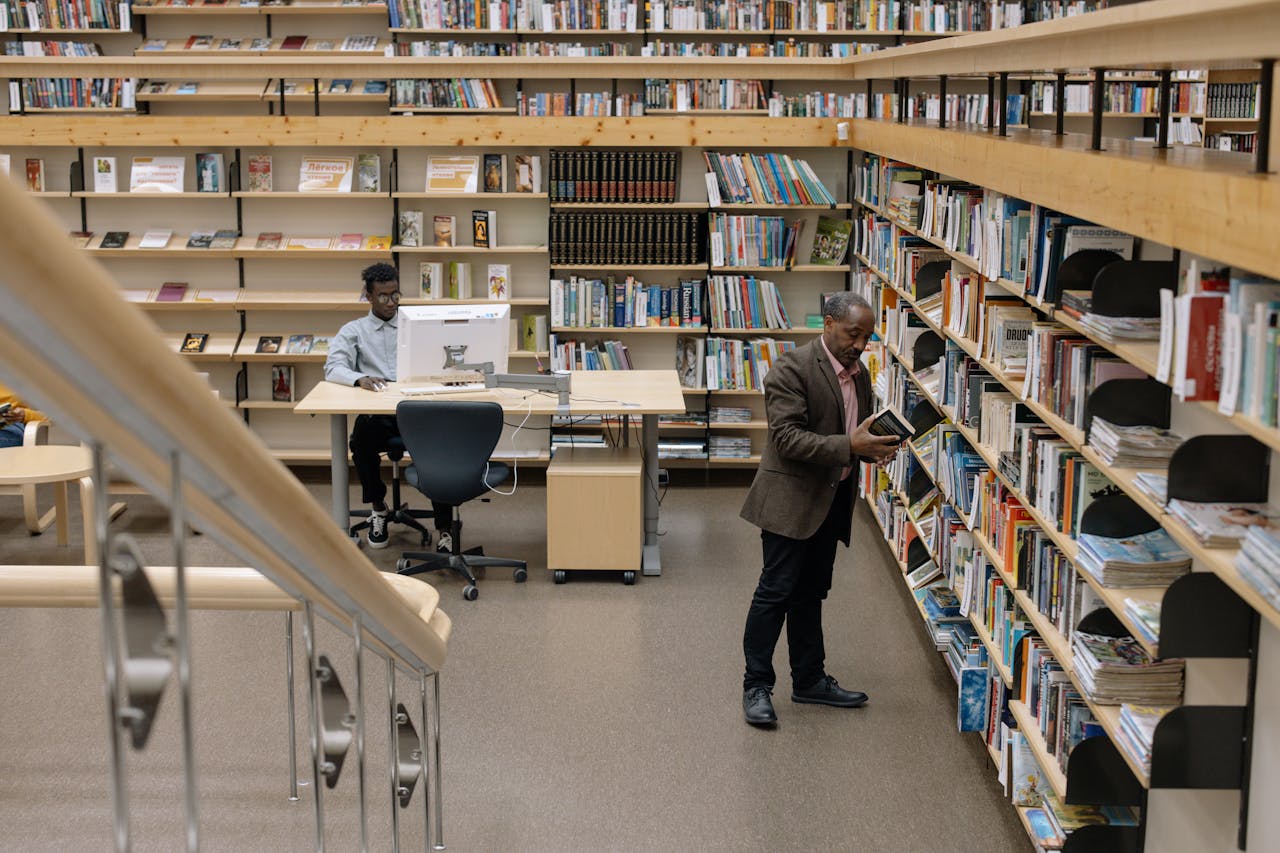 Interior of a modern library with people reading and browsing books on shelves.